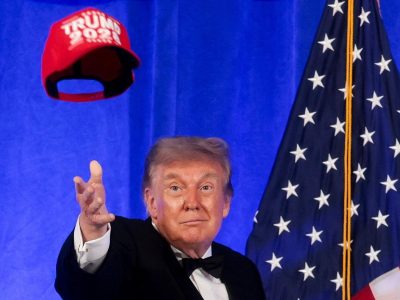 Шутки о третьем сроке и fake news. Как прошел ужин прессы с Трампом, перенесенный с апреля после стрельбы 2 Трамп, кидающий в воздух красную кепку с надписью Trump 2028, за ним — флаг США.