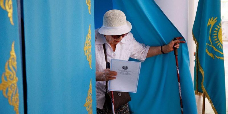 Парламентские выборы в Казахстане: партия «Адилет» набрала более 70% голосов 1 Пожилая женщина выходит из кабинки для голосования с бюллетенем в руках