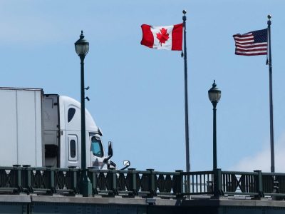 Флаги США и Канады на мосту, по которому проезжает грузовой автомобиль