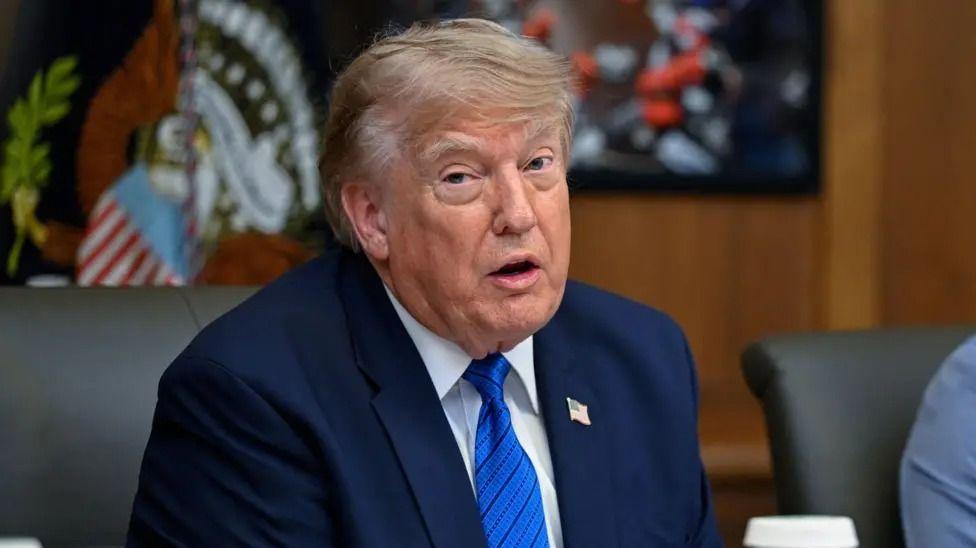 Трамп отменяет удары по Ирану при условии, что соглашение между странами будет заключено быстро 1 Дональд Трамп на заседании кабинета министров США в Кэмп-Дэвиде 31 июля: он одет в темно-синий костюм, галстук светло-голубого цвета с черными горизонтальными полосками, белую рубашку, а на пиджаке у него прикреплен значок с изображением флага США