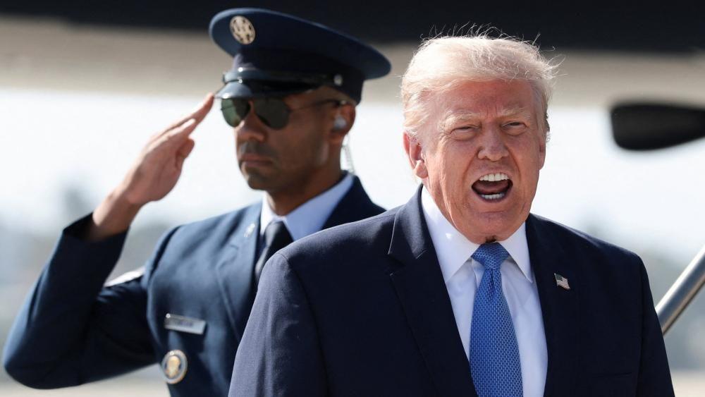 Президент США Дональд Трамп что-то громко говорит, у него за спиной военный отдает честь
