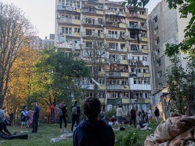 Ребенок сидит во дворе дома, по которому пришелся удар.
