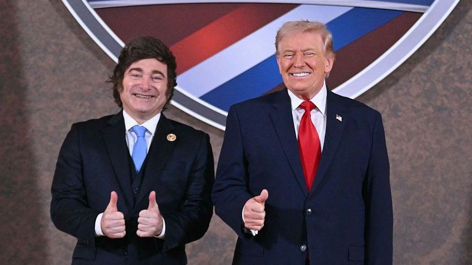 Хавьер Милей и Дональд Трамп в темных костюмах поднимают большой палец вверх в качестве знака одобрения