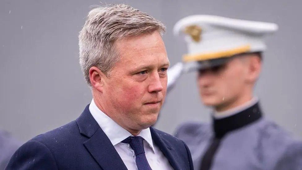 Министр армии Дэн Дрисколл прибывает на церемонию вручения дипломов в Военной академии США в Вест-Пойнте, штат Нью-Йорк; за его спиной военнослужащий отдает честь.