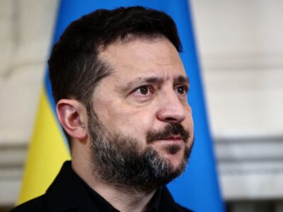 Зеленский на фоне украинского флага.
