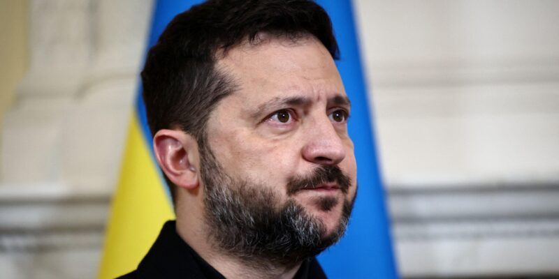 Зеленский на фоне украинского флага.