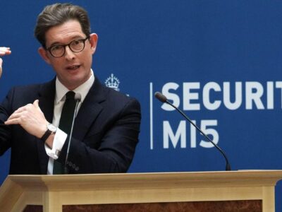 Глава британской службы контрразведки и внутренней безопасности MI5 Кен Маккаллум жестикулирует на трибуне