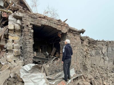 Мужчина осматривает разрушенный частный дом.