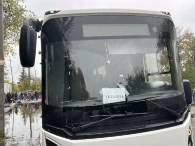 В Алешках началась эвакуация мирных жителей 2 Автобус с надписью УКРАИНА, рядом стоят люди.